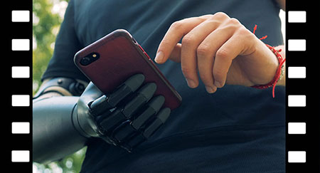A man with modern hand prosthesis looks at his phone. 4K.